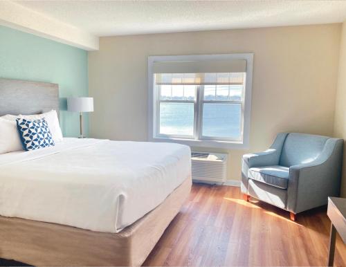 a bedroom with a bed and a chair and a window at Atlantic Beach Hotel Newport in Middletown