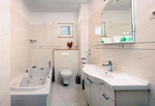 a white bathroom with a sink and a toilet at Villa Mediterana in Seget Vranjica
