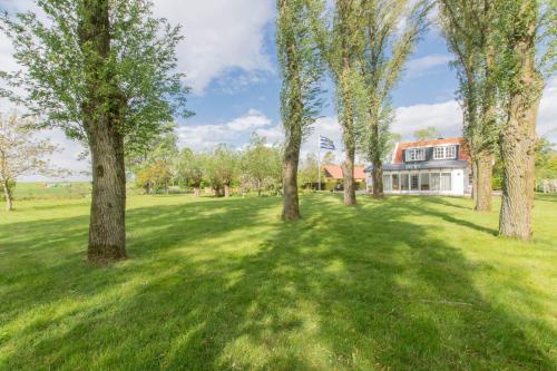 a field with trees in front of a house at Prachtig gelegen vrijstaand landhuis in Hansweert