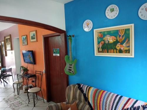 a room with a blue wall with clocks and a guitar at Hospedaria Green in Florianópolis