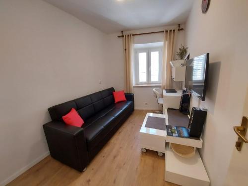 a living room with a black couch and a tv at Guest House Korunić in Korčula