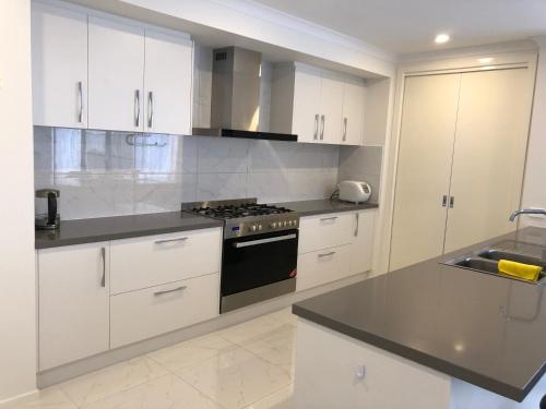 a kitchen with white cabinets and a stove top oven at Apple House Upper Point Cook in Point Cook