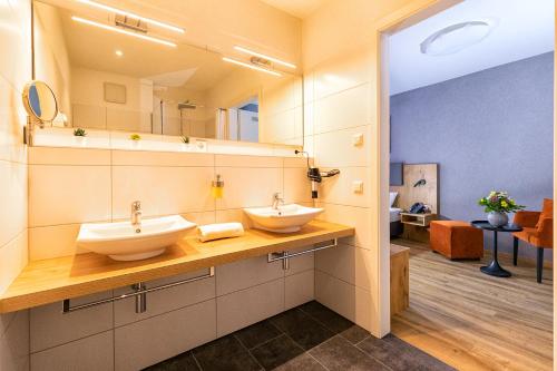 a bathroom with two sinks and a large mirror at Hotel La Mirabelle in Rheinhausen