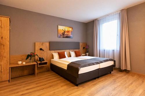 a hotel room with a bed and a window at Hotel La Mirabelle close to Europa Park in Rheinhausen