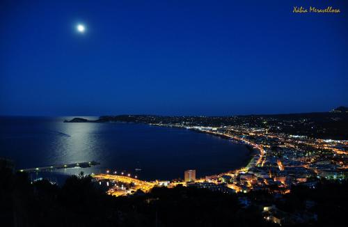 a view of a city at night with the moon at Jávea Apartment Mar in Jávea