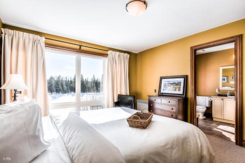 Un dormitorio con una cama y una ventana grande. en House On The Golf La Bte -10min To Tremblant 150, en Mont-Tremblant