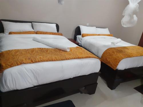 una camera con 2 letti con lenzuola bianche e arancioni di Delight Lodge a Blantyre