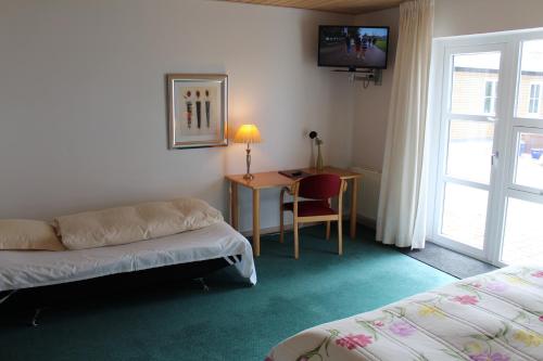 FjerritslevにあるHotel Klim Bjergのソファ、デスク、テレビが備わるホテルルームです。