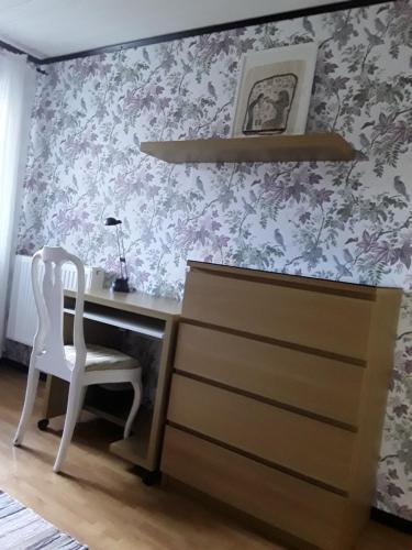 uma secretária com uma cadeira num quarto com papel de parede floral em Naturnära enkel rum B&B i Uppsala Ramstalund em Uppsala