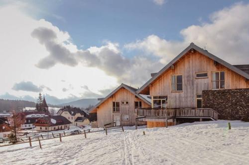 a wooden house in the snow in a town at Rodinný apartmán v srdci Šumavy in Kvilda