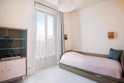 a bedroom with a bed and a large window at La Mariennée in La Rochelle