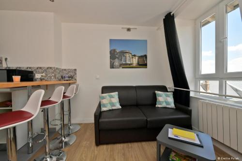 - un salon avec un canapé noir et un bar dans l'établissement Comme à la Maison - DE LA TOUR, à Saint-Quentin