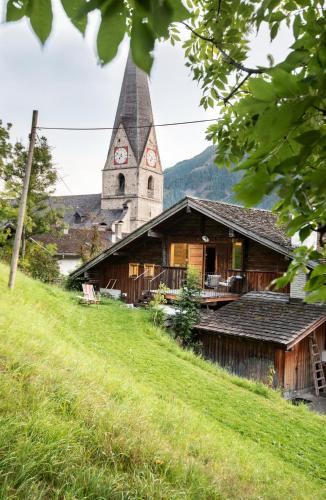 a church with a clock tower on top of a hill at Kesslerstadel in Matrei in Osttirol
