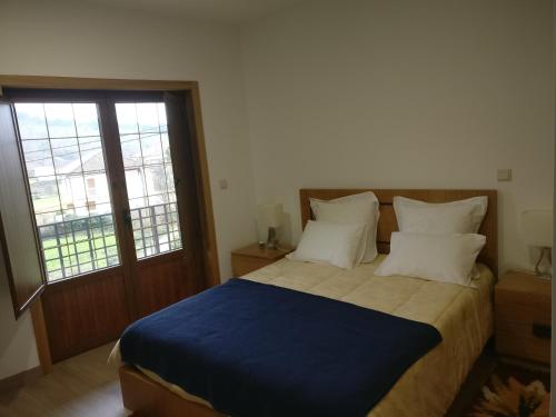 um quarto com uma cama com um cobertor azul e 2 almofadas em Casa das Olmedas em Vimioso