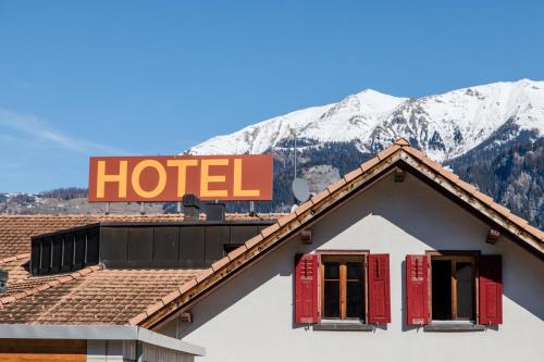 una señal de hotel en la parte superior de una casa con persianas rojas en Hotel Reich, en Cazis