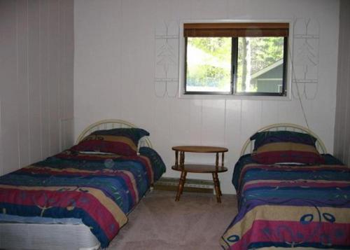 two beds in a room with a table and a window at Birch Creek #8 - 2BR/1.5BA in June Lake