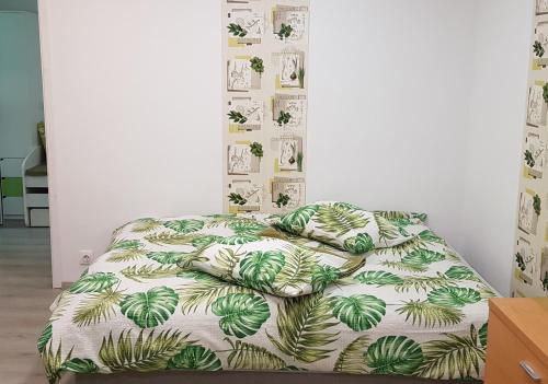 um quarto com uma cama com um edredão verde e branco em Green Apartman em Târgu-Mureş