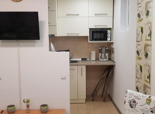 uma pequena cozinha com armários brancos e um micro-ondas em Green Apartman em Târgu-Mureş