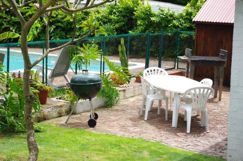 a barbecue grill and a table and chairs in a yard at Aqua Marine Guest House in Port Elizabeth