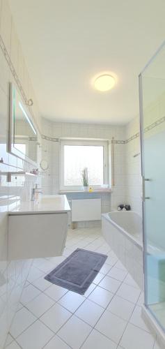 a large white bathroom with a tub and a sink at Moderne Ferienwohnung mit eigenem Garten und traumhaften Blick in Wilhelmsthal