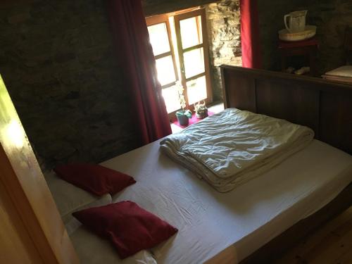 - un lit avec des draps blancs et des oreillers rouges dans l'établissement Vieux Logis een prachtige Ardeense vakantiewoning, à Vresse-sur-Semois