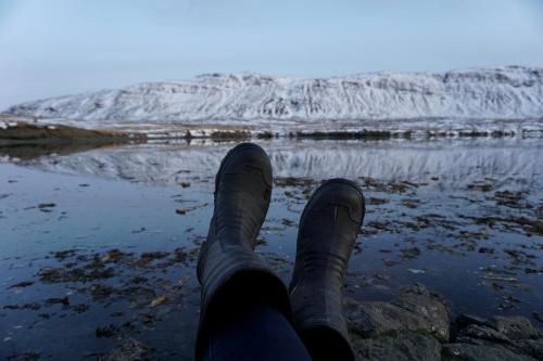 a person with their feet up on a rock near a body of water at Drangar Country Guesthouse in Drangar
