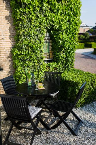 a black table and chairs in front of a wall at B&B Wilhelmina's Cottage in Ridderkerk