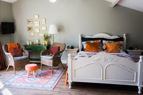 een slaapkamer met een wit bed en 2 stoelen bij B&B Wilhelmina's Cottage in Ridderkerk