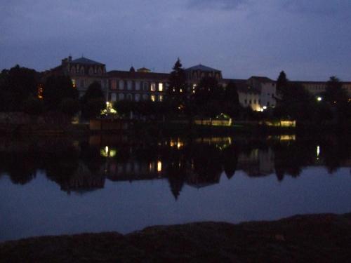 a city lit up at night with a reflection in the water at Maison du Magnolia in Confolens