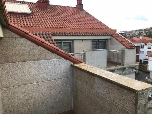 a balcony of a house with a red roof at Ático en Moaña- Playa A Xunqueira, a 15 min de Vigo in Moaña
