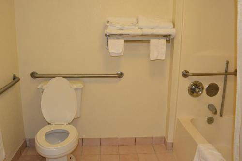 a bathroom with a toilet and a shower and towels at Travelodge by Wyndham Montgomery East in Montgomery
