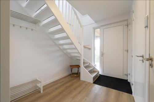 a white staircase in a white room with a door at Casa Bos Schotsman Wellness - Jacuzzi - Rental eBikes - The Kamado BBQ in Kamperland