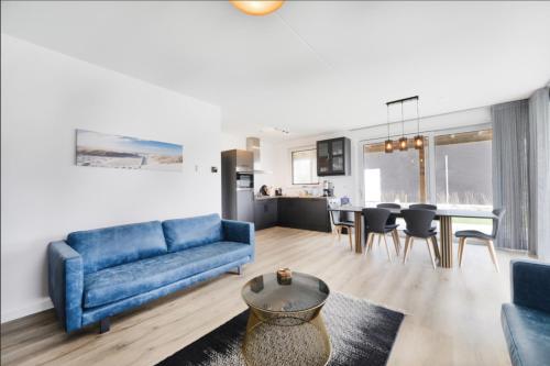 a living room with a blue couch and a table at Casa Bos Schotsman Wellness - Jacuzzi - Rental eBikes - The Kamado BBQ in Kamperland