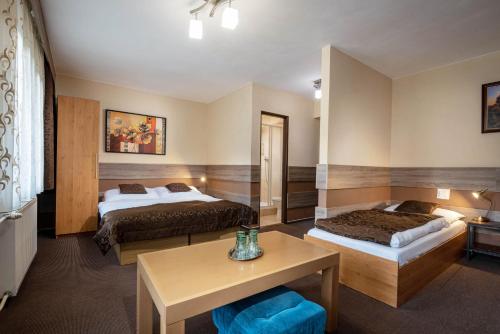 ein Hotelzimmer mit 2 Betten und einem Tisch in der Unterkunft Penzion Limba in Liptovský Ján