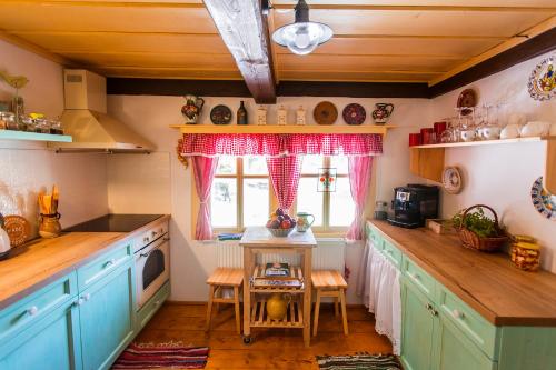a kitchen with blue cabinets and a table with a window at Chalupa Šárka in Dolni Dvur