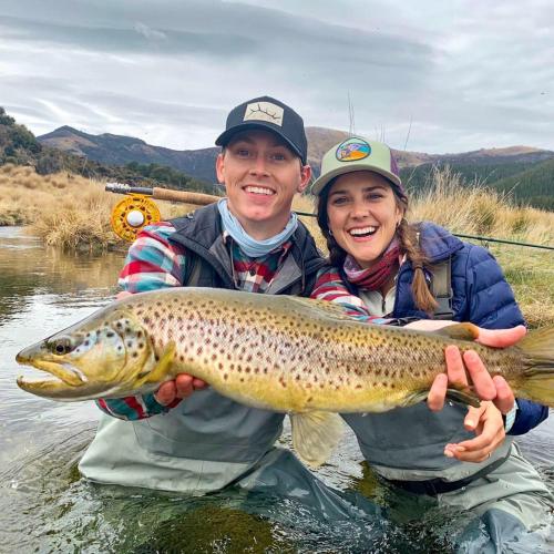 a man and a woman holding a brown trout at Fiordland Lodge in Te Anau