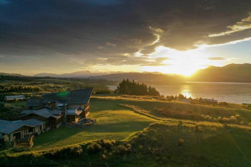 a house on a hill next to a body of water at Fiordland Lodge in Te Anau