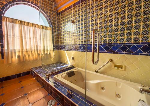 a bathroom with a tub with a window and blue tiles at Casa Estrella de la Valenciana Hotel Boutique in Guanajuato