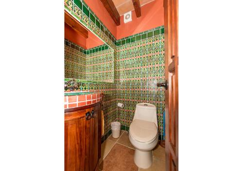 a bathroom with a toilet and a green tiled wall at Casa Estrella de la Valenciana Hotel Boutique in Guanajuato