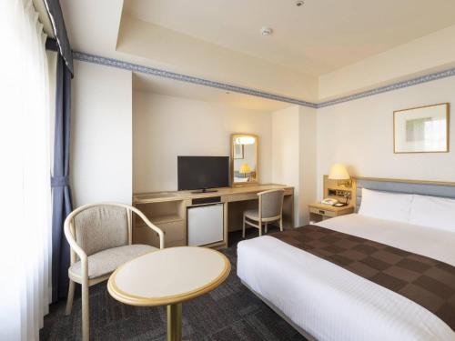 a hotel room with a bed and a desk at Hotel Sapporo Garden Palace in Sapporo
