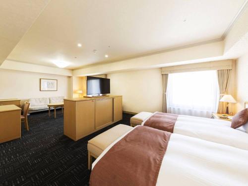 a hotel room with two beds and a flat screen tv at Hotel Sapporo Garden Palace in Sapporo