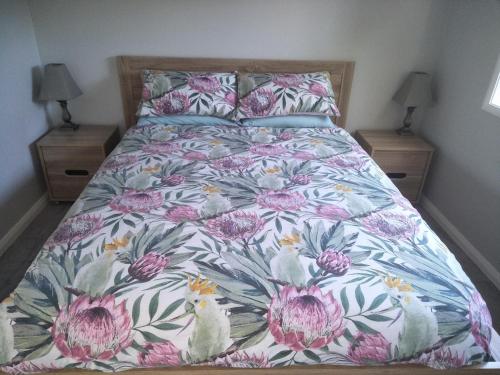 a bed with a floral bedspread and two night stands at Ashley's Retreat Umina Beach in Umina