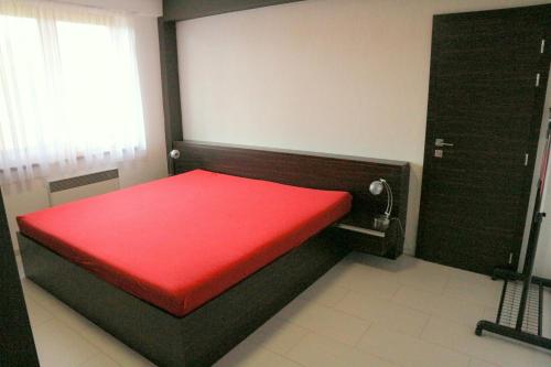 a small red bed in a room with a window at Panorama Donovaly 42-C in Donovaly
