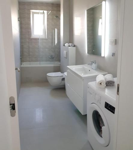 a white bathroom with a toilet sink and a washing machine at Skockica in Dugi Rat