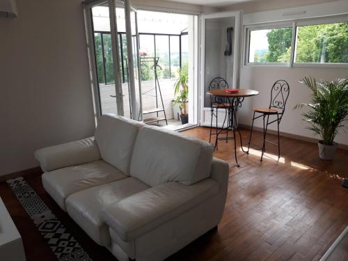 een woonkamer met een witte bank en een tafel bij L’Edaines in Bagnoles de l'Orne