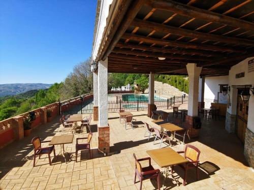 um pátio com mesas e cadeiras e uma piscina em Turismo Rural & SPA El Cercado em Bérchules