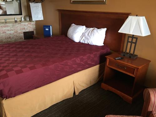 a hotel room with a bed and a table with a lamp at Rodeway Inn Sergeant Bluff - Sioux City in Sergeant Bluff