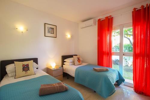 - une chambre avec 2 lits avec des rideaux rouges et une fenêtre dans l'établissement Villa Linda Vista, à Marbella