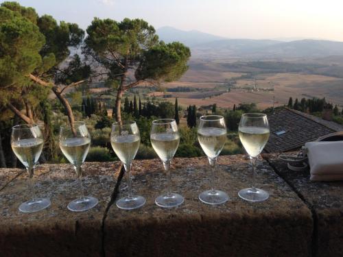 cuatro copas de vino blanco sentadas en una cornisa en Casale Santa Barbara en Montefollonico