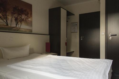 a bedroom with a white bed and a black door at Schlüter Hotel & Restaurant in Wankendorf